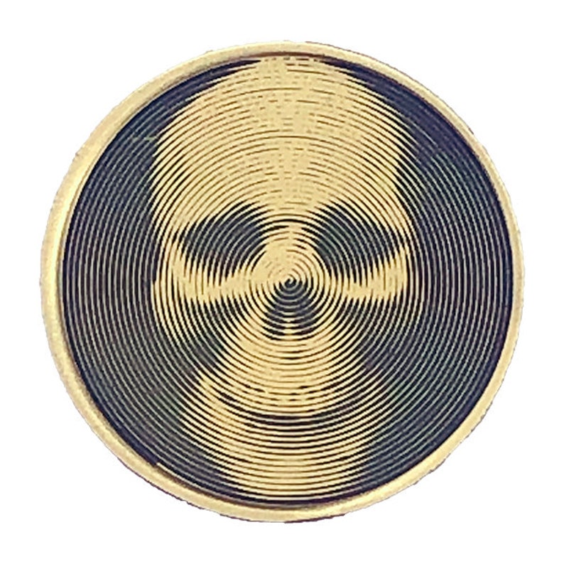 May include: A gold-colored circular coin with a black and gold skull design. The skull is created using concentric circles.