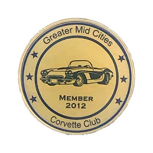 Op de afbeelding: Ronde gouden pin met een zwart-wit afbeelding van een vintage Corvette cabriolet. De pin heeft de tekst "Greater Mid Cities Corvette Club Member 2012" rond de rand.