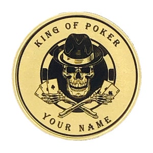 May include: Gold-colored round poker chip with a black and white skull wearing a fedora and holding playing cards. The text "KING OF POKER" is written around the top of the chip and "YOUR NAME" is written around the bottom.