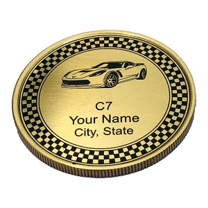 May include: Gold-colored coin with a black and white checkered border. The center of the coin features a black and white image of a Corvette C7 car. The text "C7", "Your Name", and "City, State" is printed on the coin.