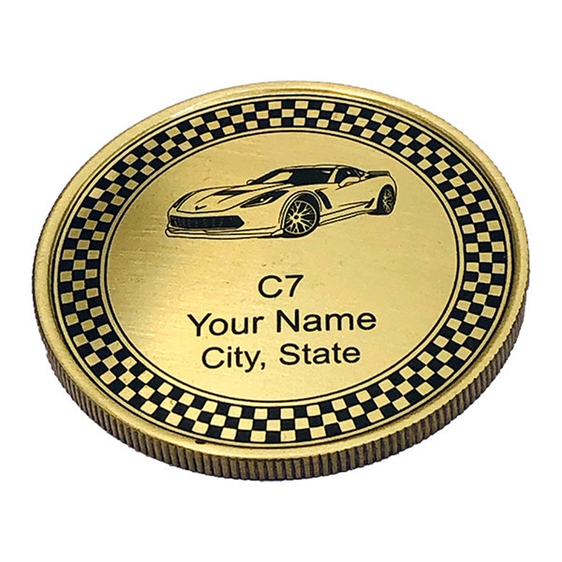 May include: Gold-colored coin with a black and white checkered border. The center of the coin features a black and white image of a Corvette C7 car. The text "C7", "Your Name", and "City, State" is printed on the coin.
