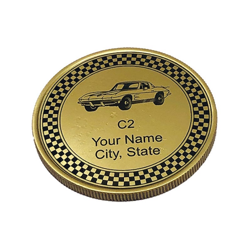 May include: Gold-colored coin with a black and white checkered border. The center of the coin features a black silhouette of a classic Corvette car. The text "C2", "Your Name", and "City, State" is printed below the car.