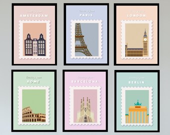 May include: Six framed art prints featuring travel-themed postage stamp designs. Each print showcases a different city: Amsterdam, Paris, London, Rome, Barcelona, and Berlin. The prints have a white border and are displayed on a white wall.