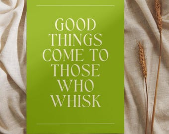 May include: A lime green rectangular sign with the text "GOOD THINGS COME TO THOSE WHO WHISK" in white. The sign is on a beige linen surface, with two stalks of wheat to the right.