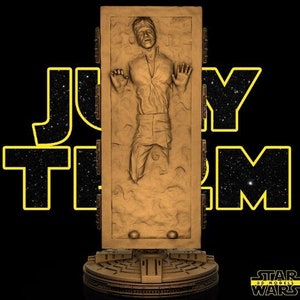 May include: A gold-colored Star Wars figure of Han Solo frozen in carbonite. The figure is on a black base with a Star Wars logo.