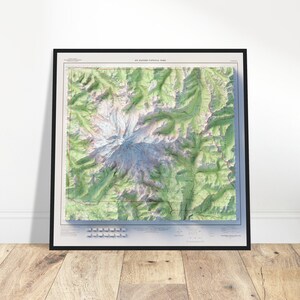 Pode incluir: Um mapa topográfico emoldurado do Parque Nacional do Monte Rainier com uma representação detalhada em relevo estilo 3D da montanha, geleiras e terreno verde circundante, com o título impresso claramente no topo da borda branca.