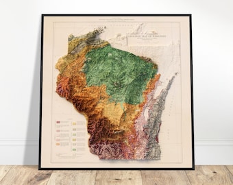 May include: Framed geologic map of Wisconsin, featuring a detailed relief map with a variety of colors. The map is in a black frame and is displayed on a wooden floor.
