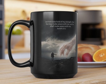 Peut inclure: Mug à café noir avec une image blanche d'une main tendue vers une personne marchant sur un chemin. Le mug porte le texte "Let him take hold of my strength, that he may make peace with me, and he shall make peace with me Isaiah 27:5".