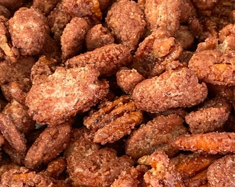 May include: A close-up of a bowl filled with pecan halves coated in a brown glaze and sprinkled with sugar crystals.