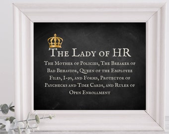 Può includere: Un cartello stampabile in bianco e nero con lettere dorate che recita "The Lady of HR" e una piccola corona dorata sopra il testo. Il cartello è incorniciato in una cornice bianca e si trova su una superficie bianca.