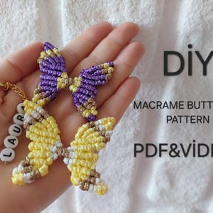 以下が含まれることがあります： 黄色、紫、茶色の手作りのマクラメ蝶のキーホルダー。キーホルダーには、金のリングと「LAURA」と書かれた白い文字ビーズが含まれています。画像には「DIYマクラメバタフライパターンPDF＆ビデオ」というテキストも含まれています。
