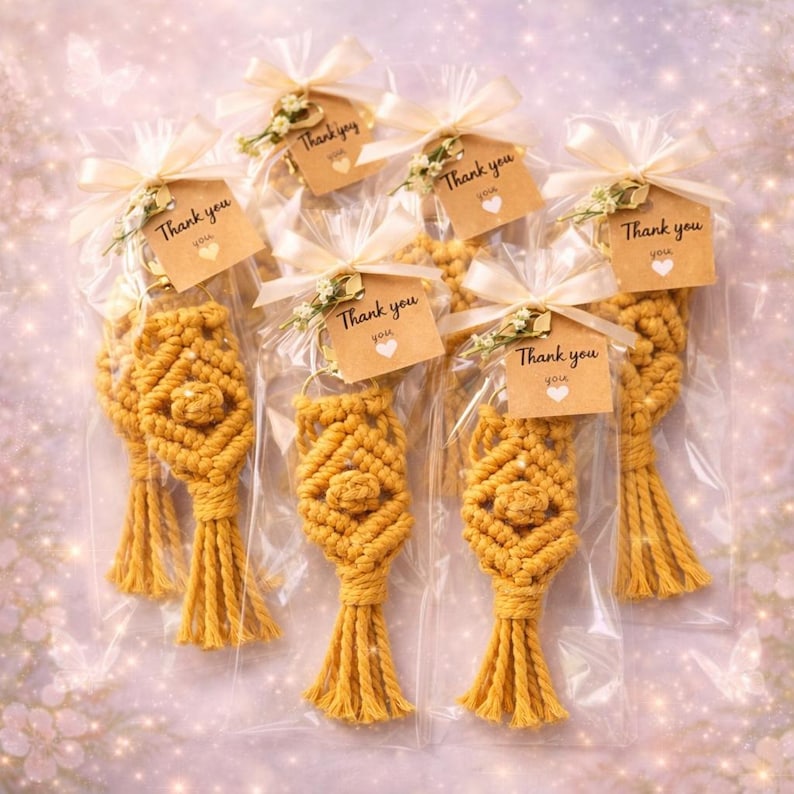 Pu&ograve; includere: Sei portachiavi in macram&egrave; giallo senape, ciascuno in un sacchetto di cellophane trasparente, legato con un nastro color crema e un piccolo cartellino con la scritta "Thank you". I cartellini hanno un piccolo cuore e rametti verdi.