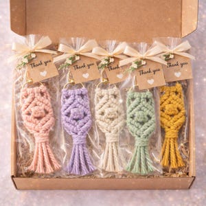 Pu&ograve; includere: Una scatola di cinque portachiavi in macram&egrave; nei toni del rosa, viola, crema, verde e giallo. Ogni portachiavi &egrave; confezionato in un sacchetto trasparente e legato con un nastro e un'etichetta con la scritta "Thank you".
