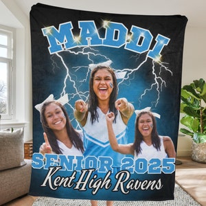 May include: A personalized black fleece blanket featuring the name "MADDI" in light blue, with a lightning bolt design. The blanket includes three photos of a smiling person in a cheerleading uniform, with the text "SENIOR 2025" and "Kent High Ravens".