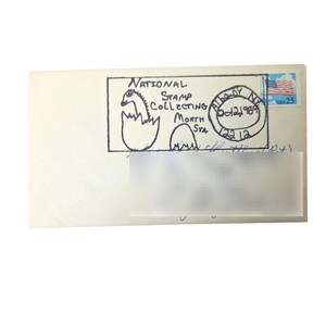 May include: An off-white envelope with a 25-cent USA flag stamp. The envelope features a hand-drawn illustration of a dinosaur hatching from an egg, with the text "NATIONAL STAMP COLLECTING MONTH STA." and a postmark from Albany, NY, dated Oct 24, 1989.