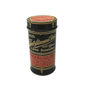 May include: A cylindrical black and red metal container for a Zenith Tibet Almond Stick. The label features gold text reading "Tibet Almond Stick will Efface 1,000 Scratches" and "It's Amazing," with additional descriptive text regarding furniture finishes.