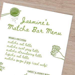May include: A white menu with green handwritten text, titled "Jasmine's Matcha Bar Menu." The menu lists matcha drinks like oat latte and strawberry latte. Green illustrations of a strainer and a hand holding a cup are also present.