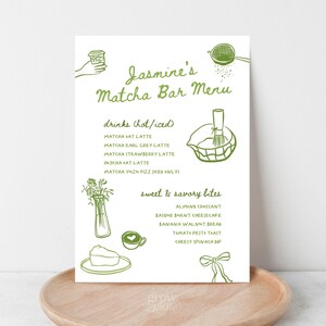 May include: A menu for Jasmine's Matcha Bar, featuring a green hand-drawn design. The menu lists hot and iced drinks like Matcha Oat Latte and Matcha Yuzu Fizz, along with sweet and savory bites such as almond croissant and cheesy spinach dip.