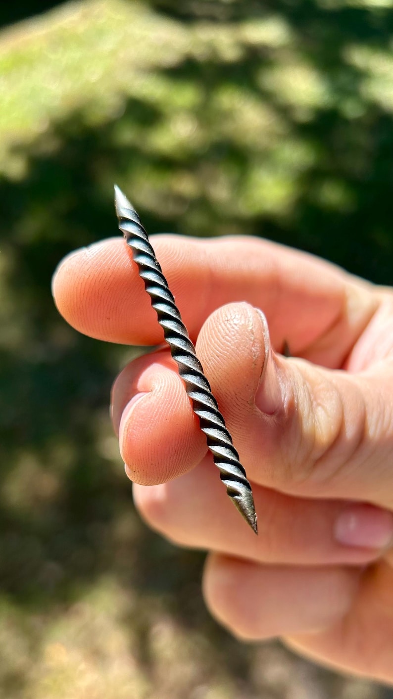 May include: A close-up of a silver, twisted metal nail.