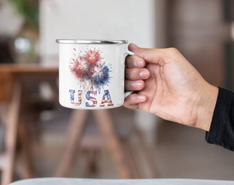 May include: White enamel mug with a red, white, and blue firework design and the word "USA" printed on the front.