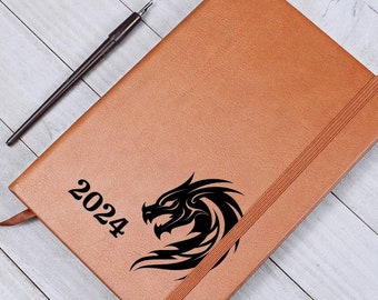 May include: A brown leather-bound journal with a black dragon design and the year 2024 engraved on the front cover.