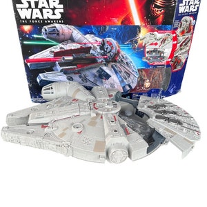 May include: A Star Wars The Force Awakens Millennium Falcon toy spaceship with a grey and red colour scheme. The spaceship is open and the interior is visible. The spaceship is on a white background.
