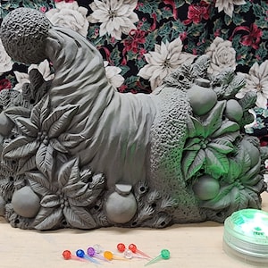 Könnte beinhalten: Ein grauer Weihnachtsstrumpf aus Keramik mit Details aus Weihnachtsstern und Stechpalme. Der Strumpf ist für kleine Lichter konzipiert und wird mit einem Satz mehrfarbiger LED-Lichter geliefert.