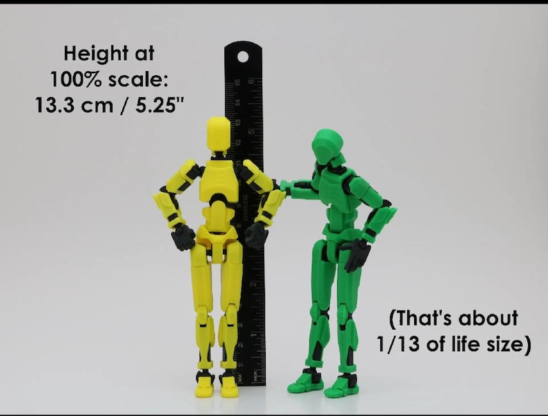 Op de afbeelding: Twee gearticuleerde actionfiguren, een gele en een groene, staan naast een liniaal. De gele figuur is 13,3 cm of 5,25 inch hoog. De tekst "Height at 100% scale: 13.3 cm / 5.25" en "(That's about 1/13 of life size)" is zichtbaar in de afbeelding.