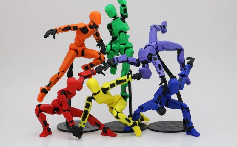 Op de afbeelding: Zes gearticuleerde actionfiguren in verschillende kleuren, waaronder rood, oranje, geel, groen, blauw en paars. De figuren zijn in verschillende dynamische poses geposeerd en staan op zwarte bases.