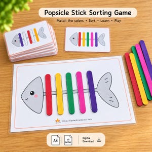 Pode incluir: Um jogo de classificação com palitos de picolé contendo uma pilha de cartões e um cartão individual mostrando o contorno de uma espinha de peixe cinza com palitos vermelhos, amarelos, verdes, rosas e roxos posicionados verticalmente por cor.