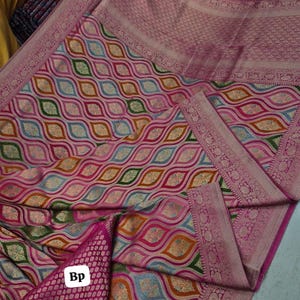 May include: A vibrant pink textile with a repeating pattern of colorful, elongated ovals in shades of pink, orange, green, and blue. The fabric has a detailed border and a separate piece with the letters "Bp".