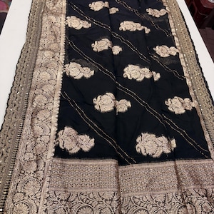 Elegant Khaddi Organza saree featuring intricate allover weaving motifs, adorned with shimmering Saroski highlights.
