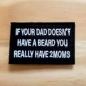 May include: A black rectangular patch with white embroidered text that reads: "IF YOUR DAD DOESN'T HAVE A BEARD YOU REALLY HAVE 2 MOMS."