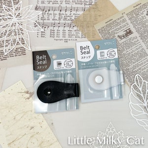 May include: Two packages of black and silver belt seals. The packages are labeled "Belt Seal" in Japanese and English. The seals are designed to hold notebooks, journals, and other items together.