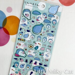 Puede incluir: Una hoja de pegatinas con varios personajes de tiburones ballena azules e ilustraciones de gatos negros. Las pegatinas tienen un fondo azul claro con texto japon&eacute;s y acentos de burbujas. El texto "Little Milky Cat" est&aacute; en la parte inferior.