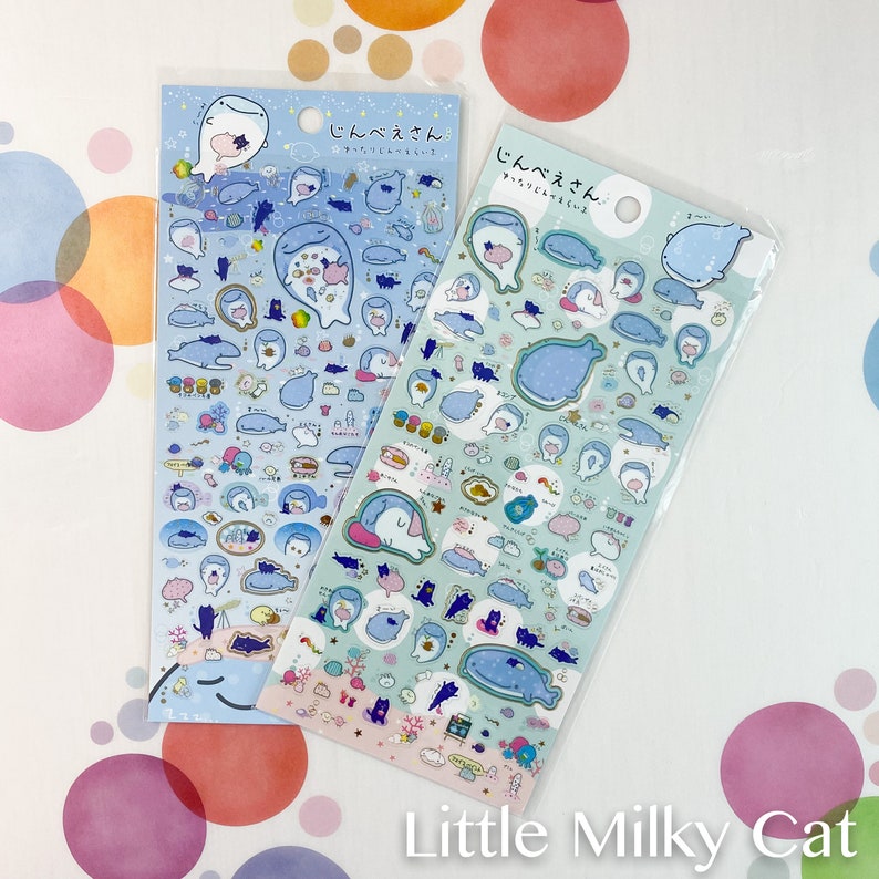 Puede incluir: Dos hojas de pegatinas con ilustraciones de un personaje de ballena en varias poses y entornos. Las pegatinas son principalmente azules y blancas, con acentos rosas y amarillos. El texto "Little Milky Cat" est&aacute; en la parte inferior.