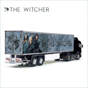 May include: A black semi-trailer truck with a white trailer. The trailer has a large image of the characters from the TV show "The Witcher" and the words "The Witcher" on the side. The trailer is decorated with a wolf's head and a map of the fictional world.