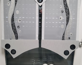 May include: Gray and white sheer window curtain with a black and silver geometric design. The curtain has a decorative valance with a black button and a curved bottom edge.
