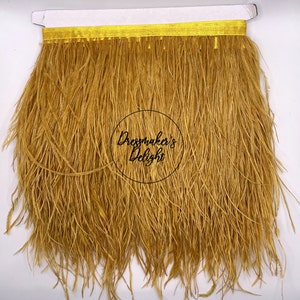 Puede incluir: Una tira de ribete de plumas de avestruz doradas con un respaldo de cinta de satén amarilla. El ribete mide aproximadamente 15 cm de ancho y es perfecto para agregar un toque de elegancia a cualquier proyecto.
