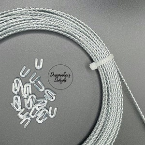 May include: A roll of silver braided wire with a white plastic tie and a pile of silver metal u-shaped hooks.