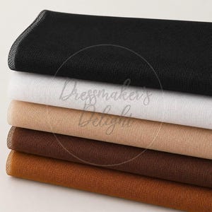 May include: A selection of fabric rolls in black, white, beige, brown, and rust. The fabric has a fine mesh weave. The image includes the text "Dressmakers Delight".