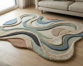 Puede incluir: Alfombra abstracta con un diseño fluido en tonos beige, azul, verde y marrón. Los patrones en capas de la alfombra crean una sensación orgánica. Se coloca sobre un suelo de madera, añadiendo un toque moderno a la habitación.