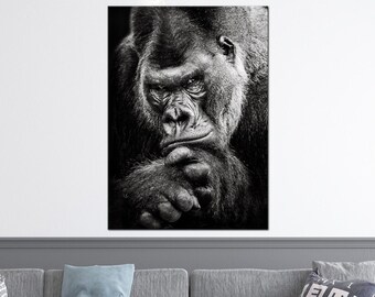 Könnte beinhalten: Schwarzweißfoto eines Gorillas, der direkt in die Kamera schaut. Der Gorilla sitzt mit gekreuzten Armen und leicht geneigtem Kopf.