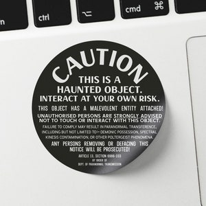 May include: A black and white round sticker with the word "CAUTION" in large white letters. The sticker warns that the object is haunted and to interact at your own risk. The sticker also includes a warning about paranormal transference, demonic possession, spectral kinesis contamination, and other poltergeist phenomena. The sticker also states that anyone removing or defacing the notice will be prosecuted. The sticker includes the text "Article 13, Section 6966-333" and "Dept. of Paranormal Transmission."