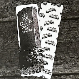 May include: Two Halloween-themed bookmarks. One shows a tombstone with the text "LET ME R.I.P. (READ IN PEACE)". The other is white with the words "Creatively Haunted" repeated in a black, stylized font.