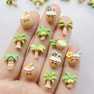 May include: A collection of miniature resin charms featuring tropical themes. The charms include smiling coconuts with straws and umbrellas, and various palm tree designs in shades of green, tan, and brown.