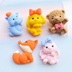 Puede incluir: Colección de figuras de animales coloridas: un hipopótamo azul, un perro amarillo, un oso de peluche marrón, un zorro naranja y un conejo rosa. Cada figura tiene un lazo. Adecuado para manualidades o decoración.