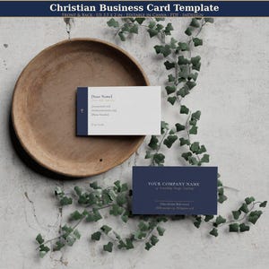 Könnte beinhalten: Christliche Visitenkarten-Vorlage in Marineblau und Weiß. Die Vorderseite der Karte zeigt ein Kreuz und den Text "Dear Name". Die Rückseite der Karte trägt den Text "Your Company Name". Die Karten liegen auf einem Holztablett mit Grünzeug.
