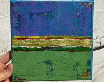 May include: Abstract painting on canvas with a blue, purple, yellow, green, and gold colour scheme. The painting is divided into horizontal bands of colour.