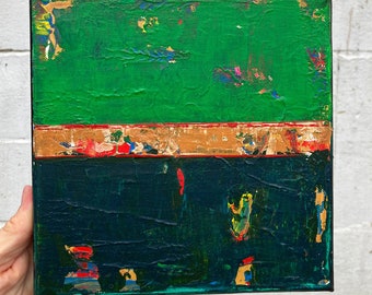 May include: Abstract canvas painting with a textured surface. The artwork displays a vibrant green upper section, a gold and red band, and a deep teal lower section. The painting is square and has a black border.